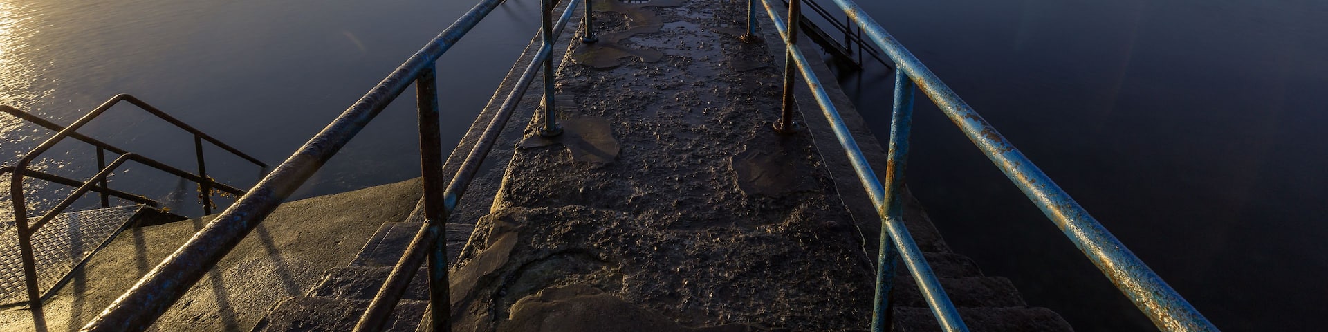 A pier extending into calm waters with a clear sky.
