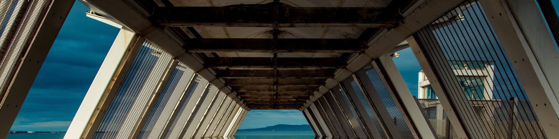 Modern polygon-shaped peatonal bridge in an Irish train station with a view at the beach.Booterstown dart station, Dublin, Ireland.
