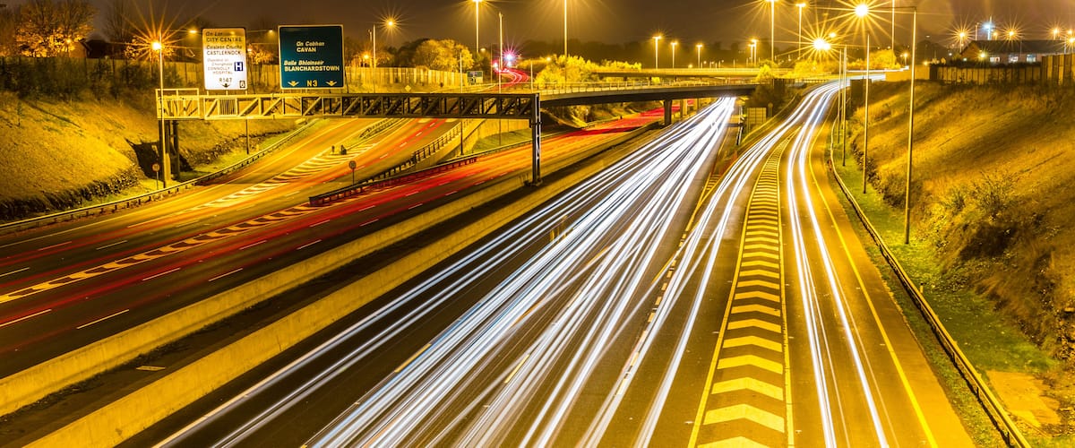 A multi-lane highway at night with light trails from moving vehicles.