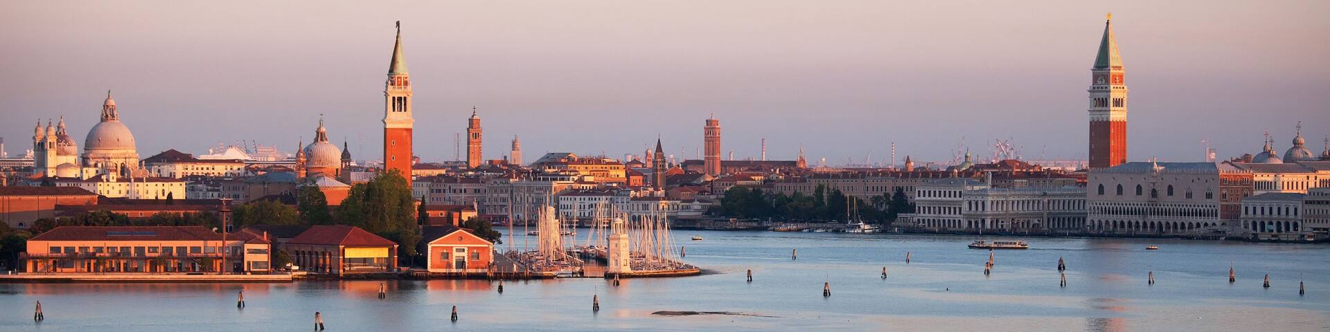 A panoramic view of a cityscape with prominent domed buildings, a large tower, and a waterfront with boats.