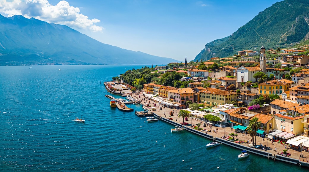 Aerial view of Limone sul Garda, a colorful lakeside town in Italy nestled between Lake Garda and steep mountains under a bright blue sky