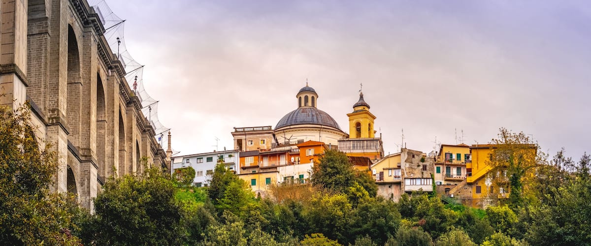 A historic building with a dome and bell tower, surrounded by colorful residential buildings and lush greenery.
