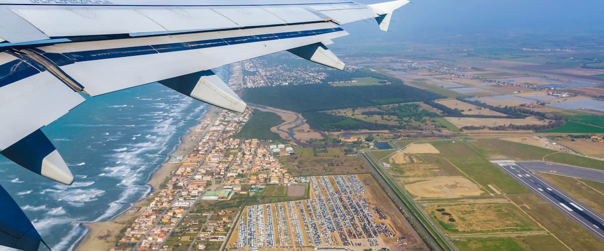 Looking through window aircraft at wing of airplane flying over the fiumicino where is situated the Fiumicino International Airport "Leonardo da Vinci.
