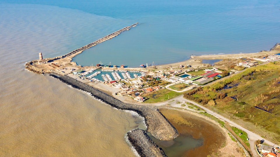 An aerial view of a coastal town with a lighthouse, marina, and residential area.