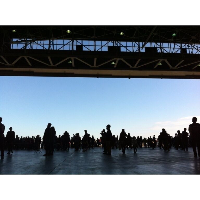 A large open space with a metal roof structure and a crowd of people.