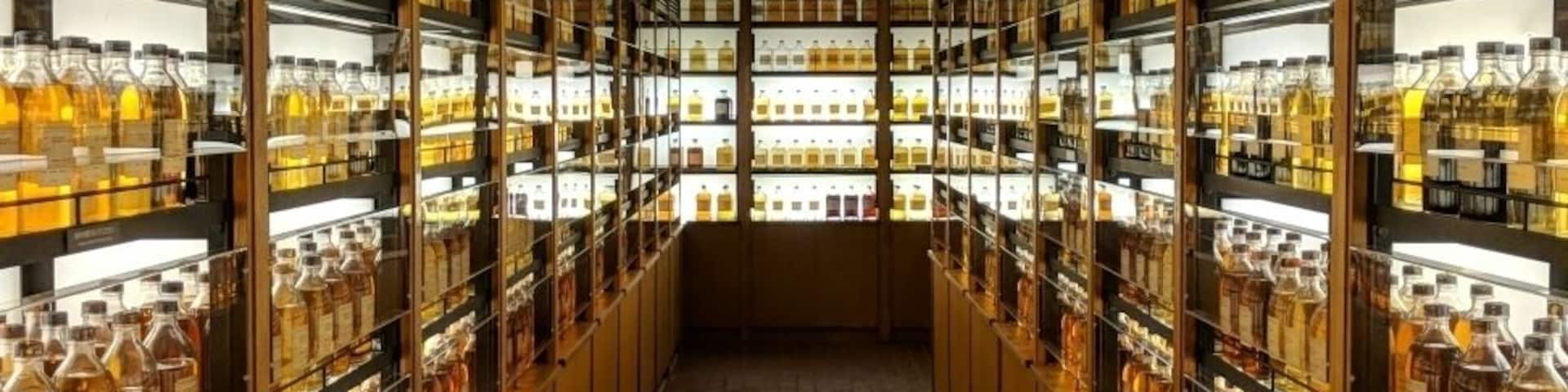 Un pasillo largo y estrecho flanqueado por estantes llenos de botellas, probablemente una licorería o bar.
