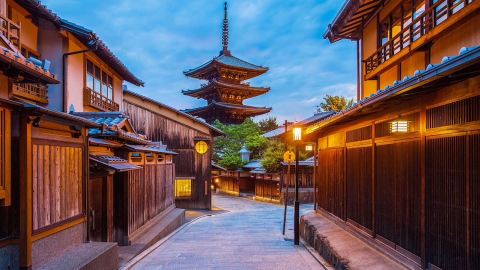 A traditional Japanese street with wooden buildings, a pagoda, and a stone pathway.