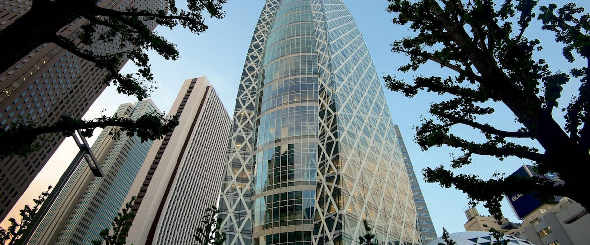 A modern skyscraper with a unique geometric design, surrounded by other tall buildings and trees.