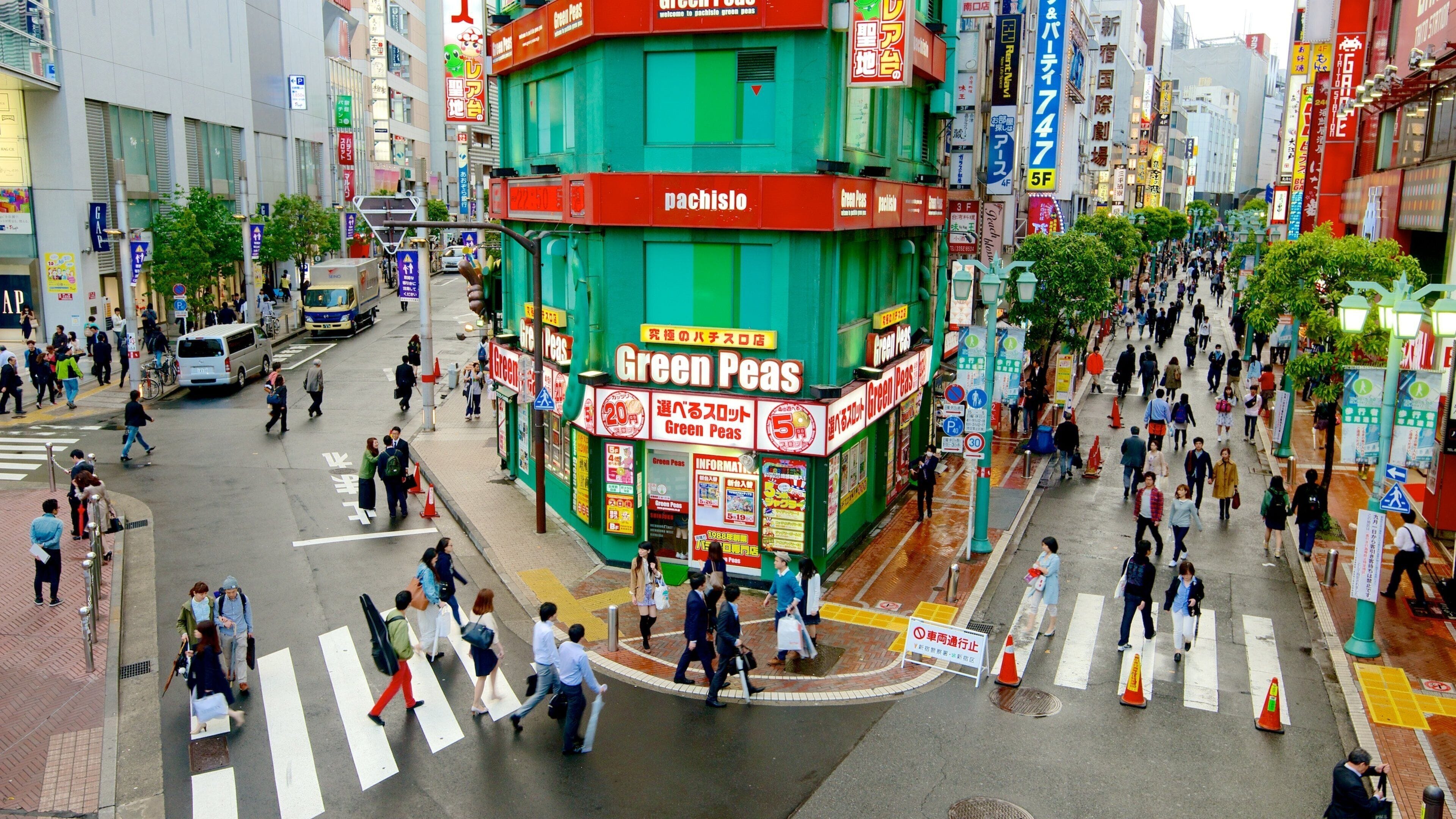 A busy urban street with a prominent green building labeled "Green Peas."