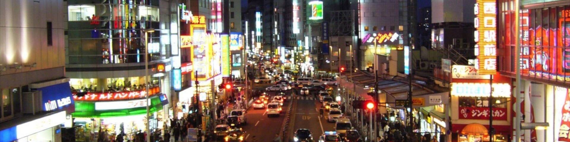 A busy urban street at night with illuminated billboards and a prominent Epson sign.