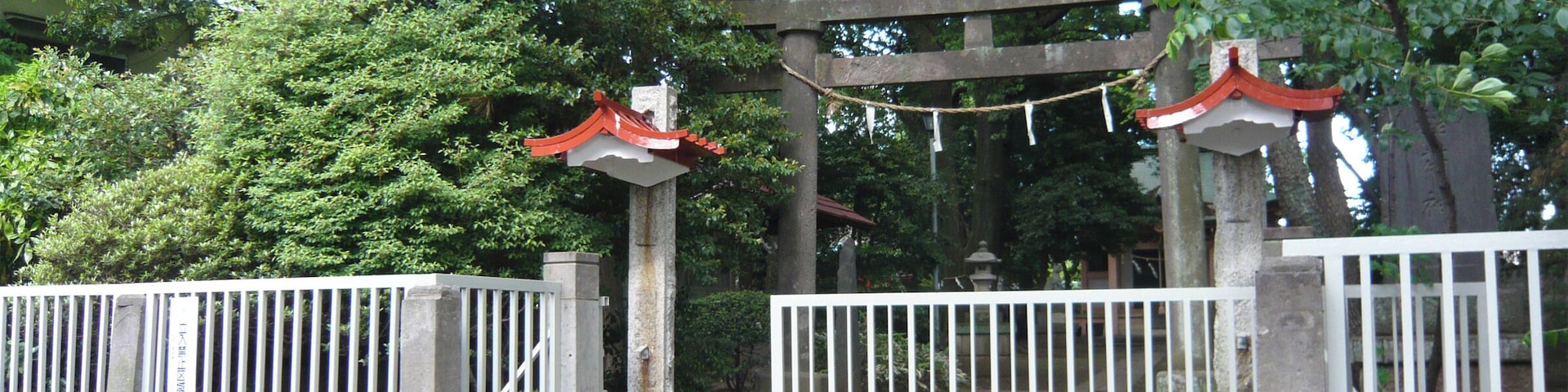 A traditional Japanese torii gate with a wooden structure and red roof, leading to a stone staircase.