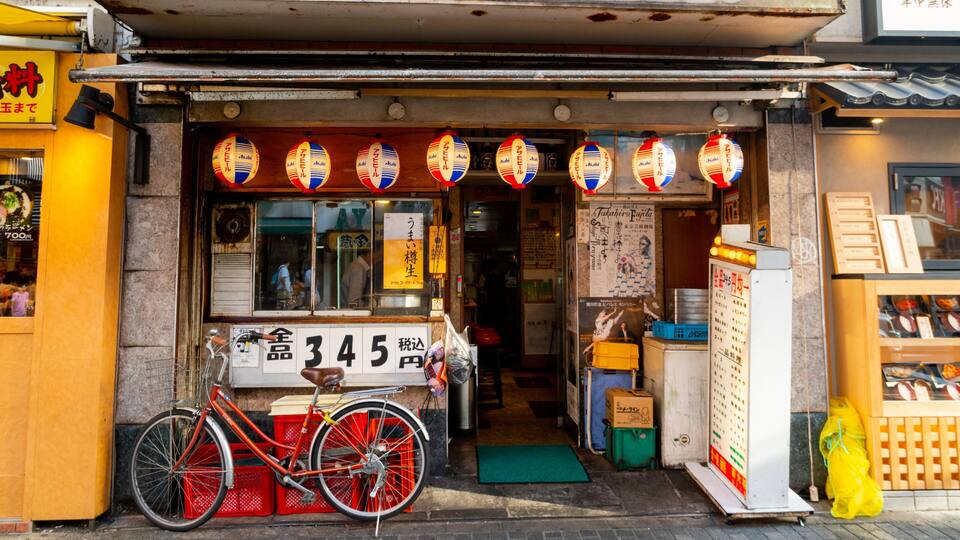 Ein Laden mit traditionellen japanischen Laternen, einem Fahrrad und einem Schild mit japanischen Schriftzeichen.