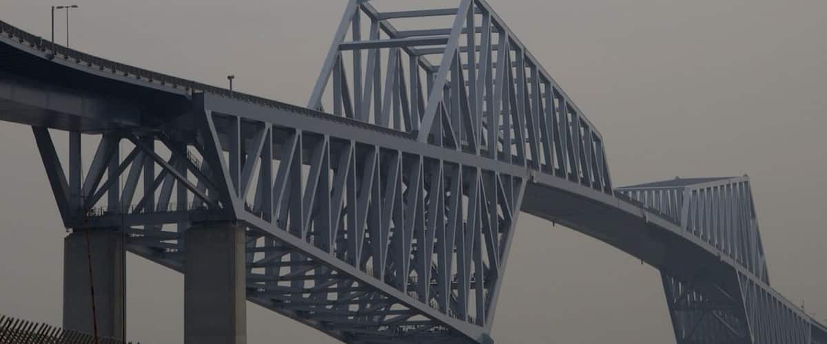 A bridge with a plane flying overhead.