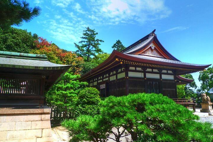 Un edificio japonés tradicional con techo curvo, rodeado de exuberante follaje y árboles.