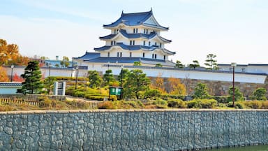 Un castillo japonés tradicional con varios niveles y un muro de piedra en primer plano.