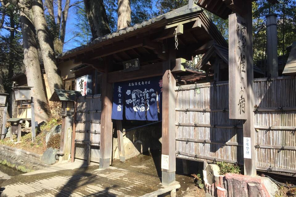 A traditional Japanese torii gate with wooden pillars and a bamboo fence.