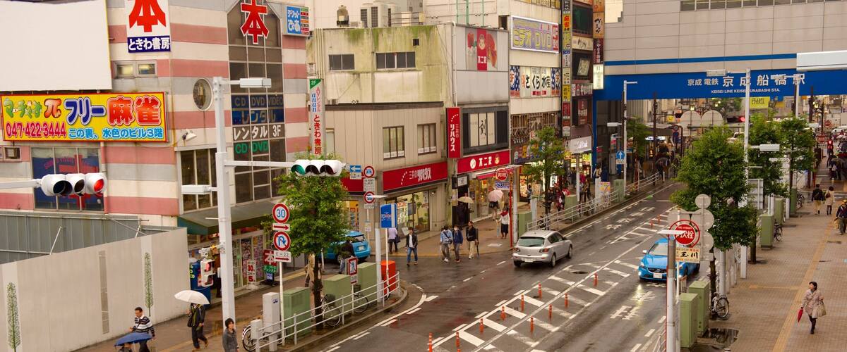 A busy urban street with crosswalks, traffic cones, and pedestrians.