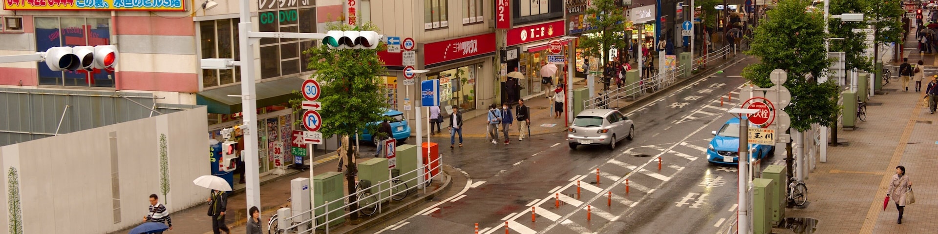 A busy urban street with crosswalks, traffic cones, and pedestrians.