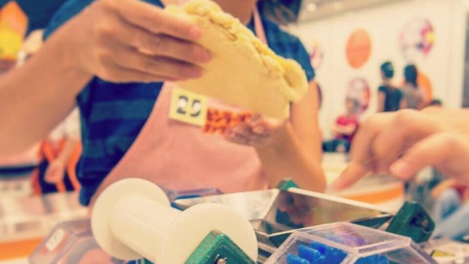 A person holding a yellow object, possibly a food item, with a number tag.
