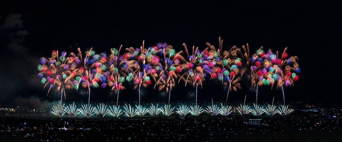 A nighttime fireworks display over a cityscape.