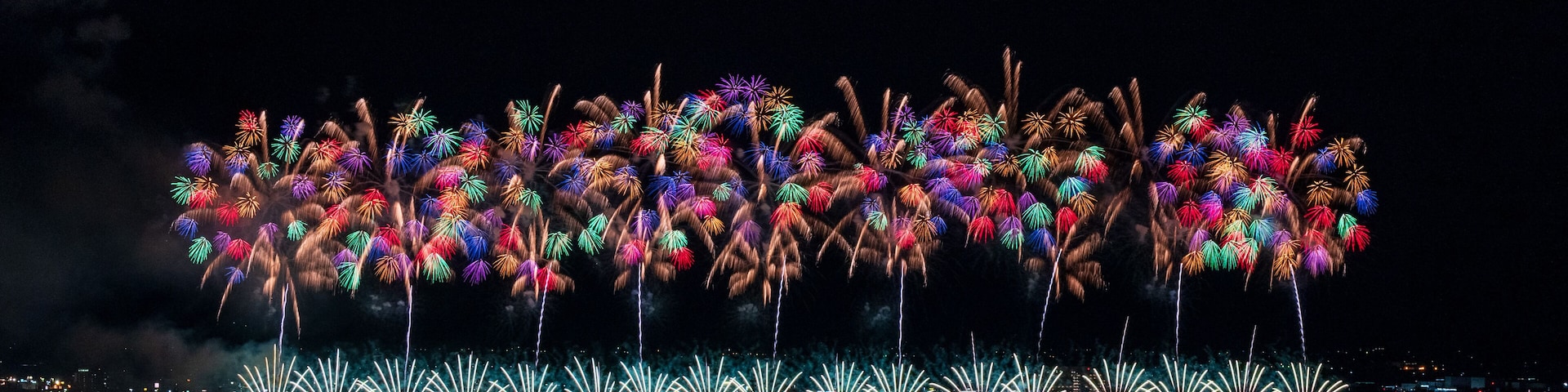 A nighttime fireworks display over a cityscape.