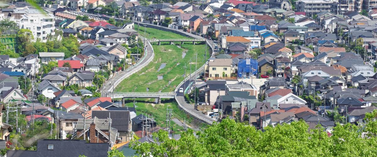 A densely populated urban area with numerous houses, a curved road, and a bridge.