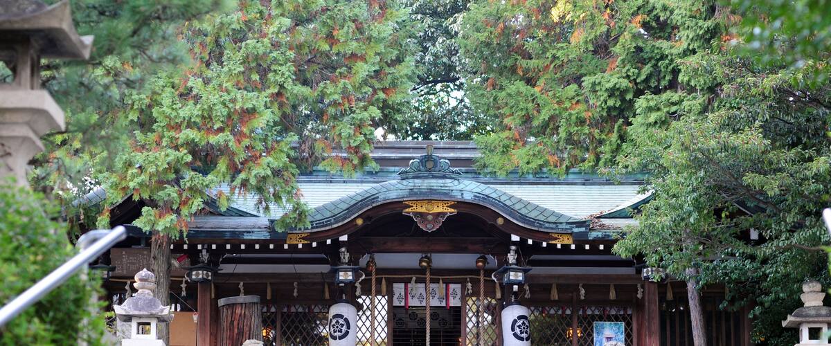 A traditional Japanese temple with a curved roof, wooden gates, and stone lanterns.