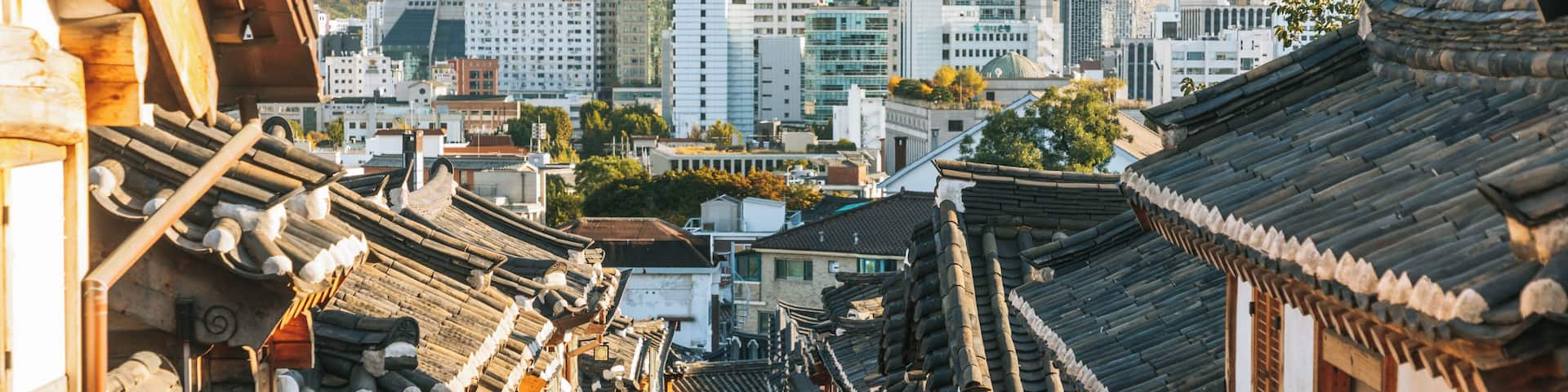A bustling street with traditional Korean architecture, modern buildings, and a crowd of people.