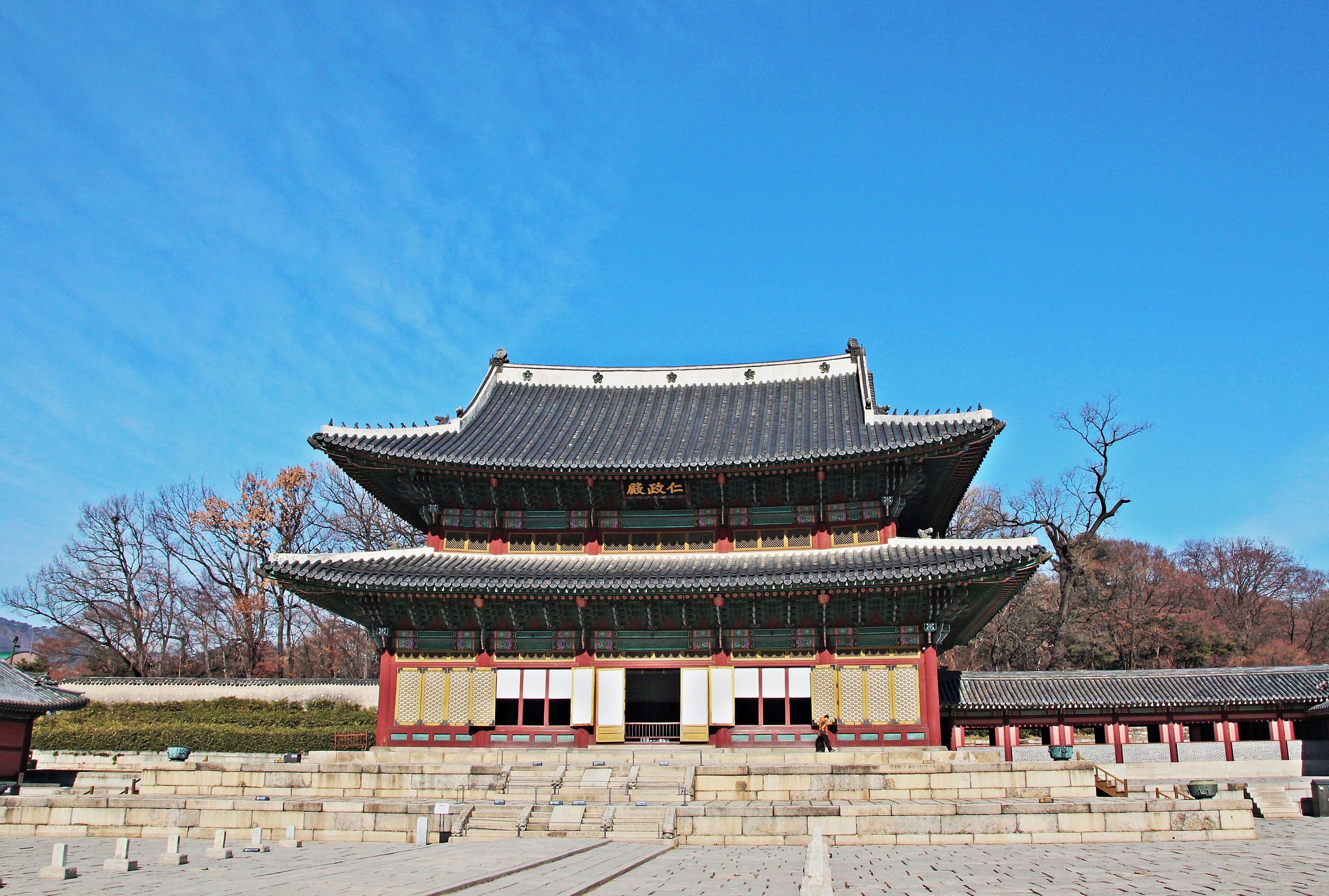 Um edifício coreano tradicional com um telhado em vários níveis e decorações em vermelho e dourado.
