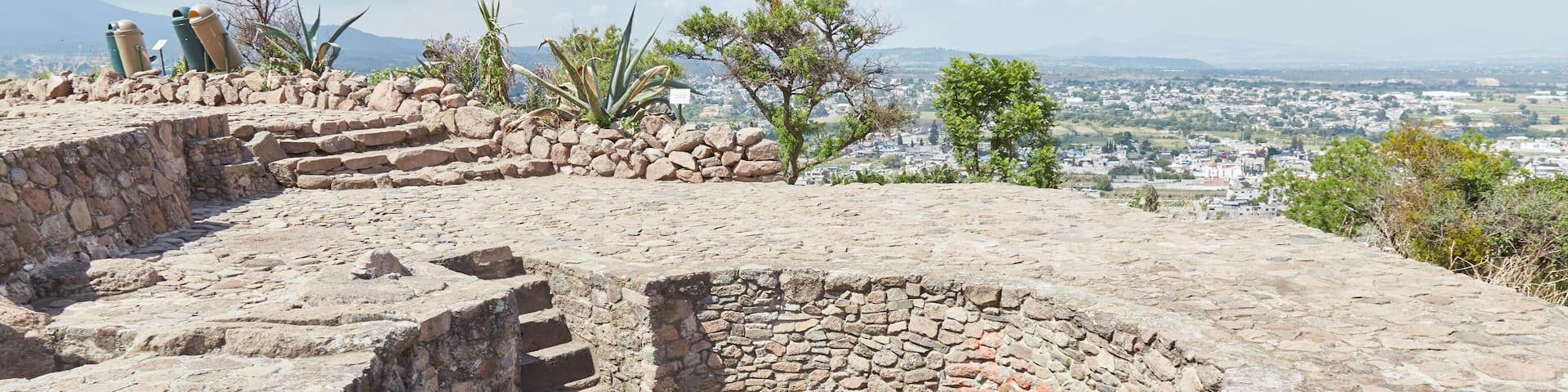 An ancient stone structure with a circular well, surrounded by a stone wall and steps leading up to it.