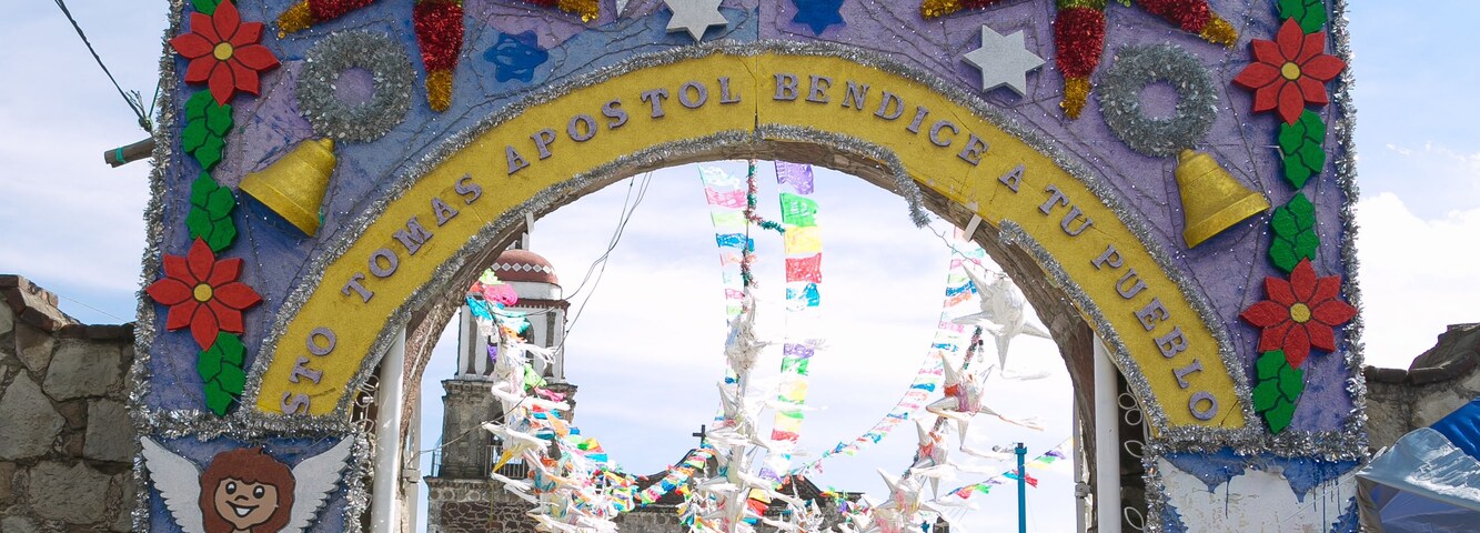 Un arco colorido con figuras religiosas y adornos, que conduce a una iglesia.