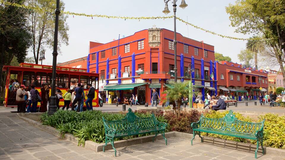 A vibrant street with a red building, green benches, and a tram.