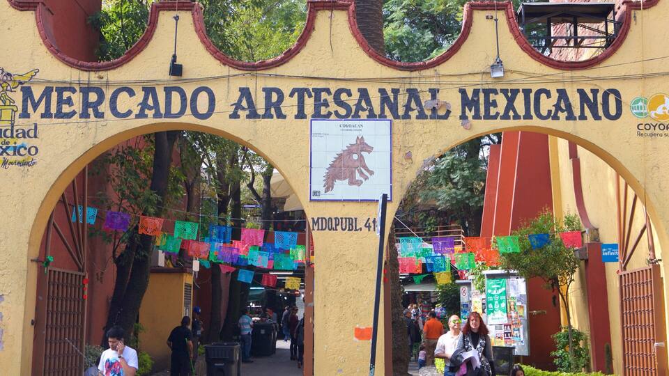 An entrance to Mercado Artesanal Mexicano with colorful decorations and a sign featuring a coyote.