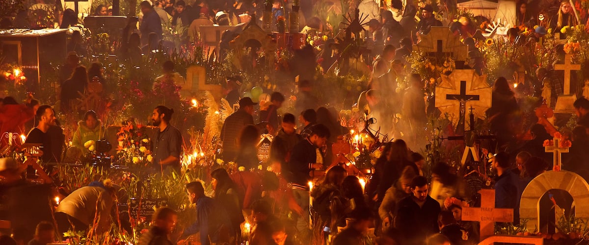 A crowded outdoor event with people gathered around illuminated structures and candles.