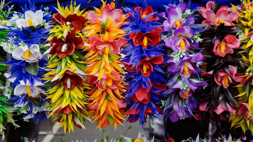 Eine Vielfalt bunter künstlicher Blumen in einer Marktszene.