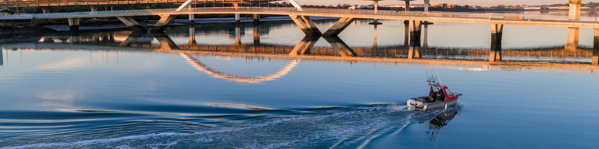 Un puente sobre un río tranquilo con una barca al frente.