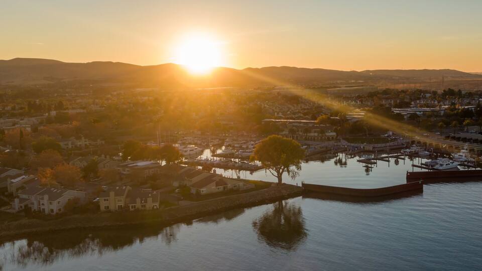 A sunset over a residential area with a marina and calm water reflecting the sky.