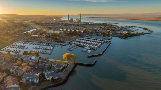 Aerial view of Pittsburg, California, USA, at sunset. The image shows the city's marina, waterfront homes, and a power plant in the distance.