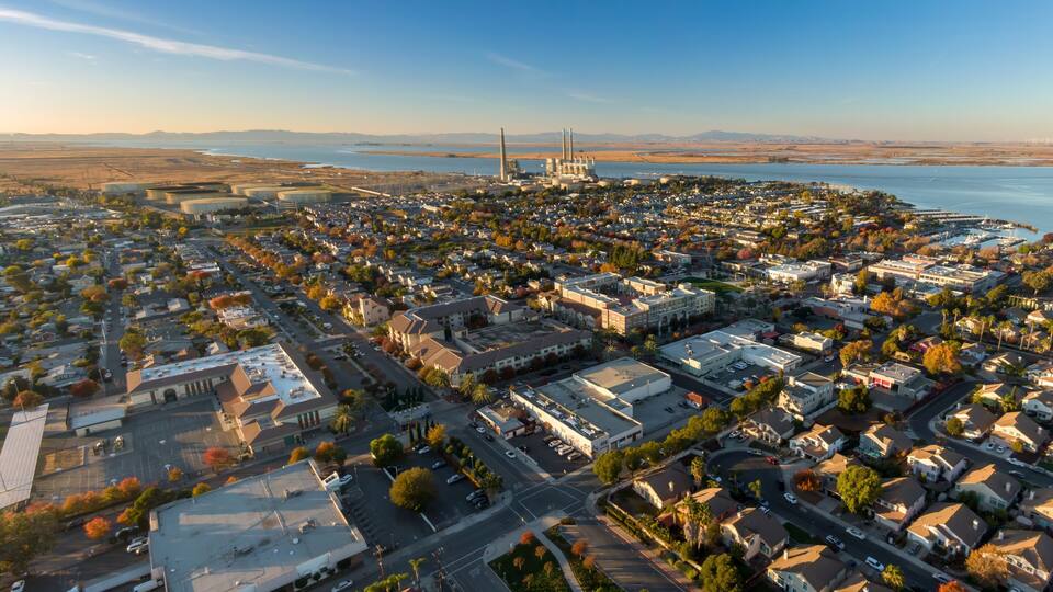 A coastal cityscape with residential areas, a marina, and industrial facilities.