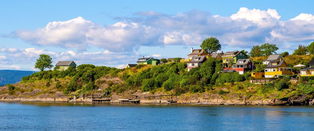 Panoramic view of Lindoya island on Oslofjord harbor near Oslo, Norway, with summer cabin houses at wooded shoreline in early autumn