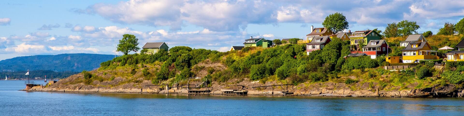 Panoramic view of Lindoya island on Oslofjord harbor near Oslo, Norway, with summer cabin houses at wooded shoreline in early autumn