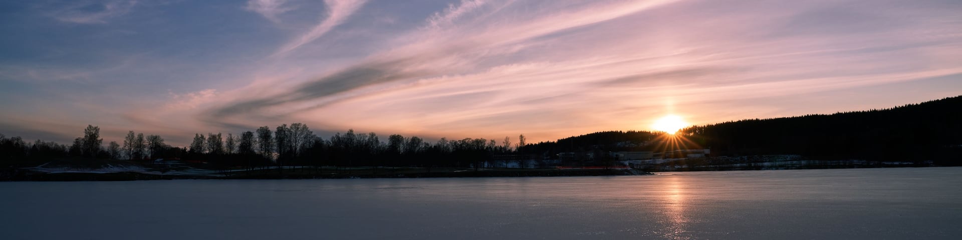 A frozen lake with a sunset in the background.