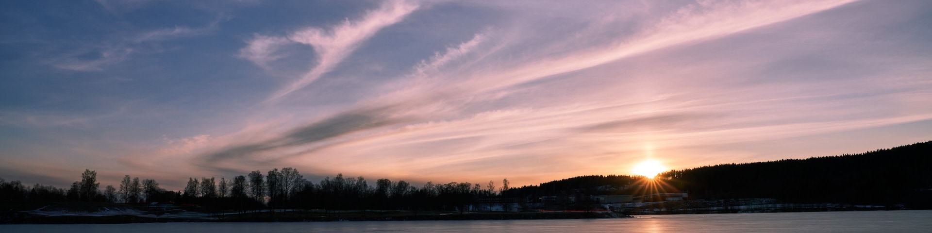Un lago congelado con un atardecer al fondo.