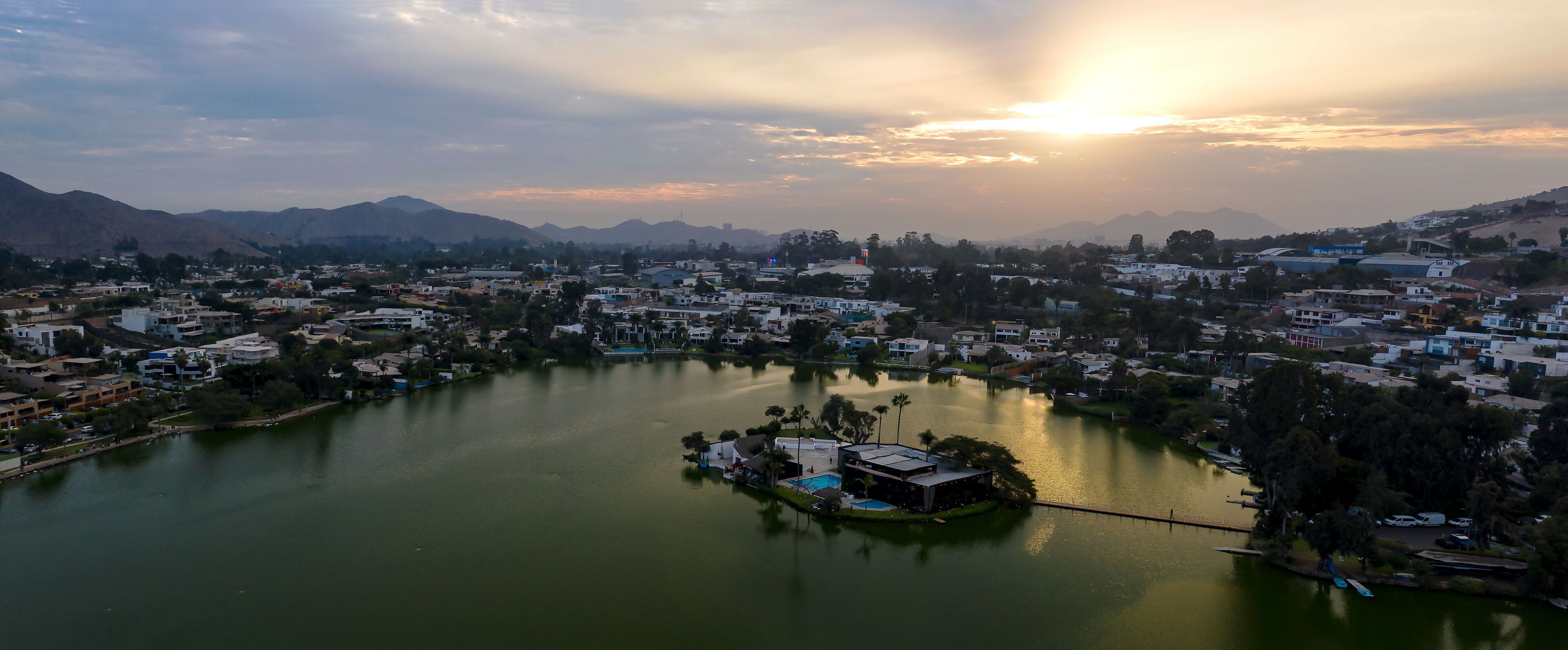 Lima, Perú - May 4 2019:  Panoramic aerial view of Las Lagunas in La Planicie. Lake at sunset with houses of high class.