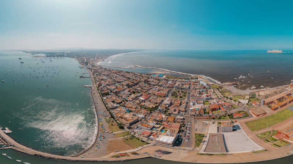 An aerial view of a coastal town with a marina, beach, and industrial area.