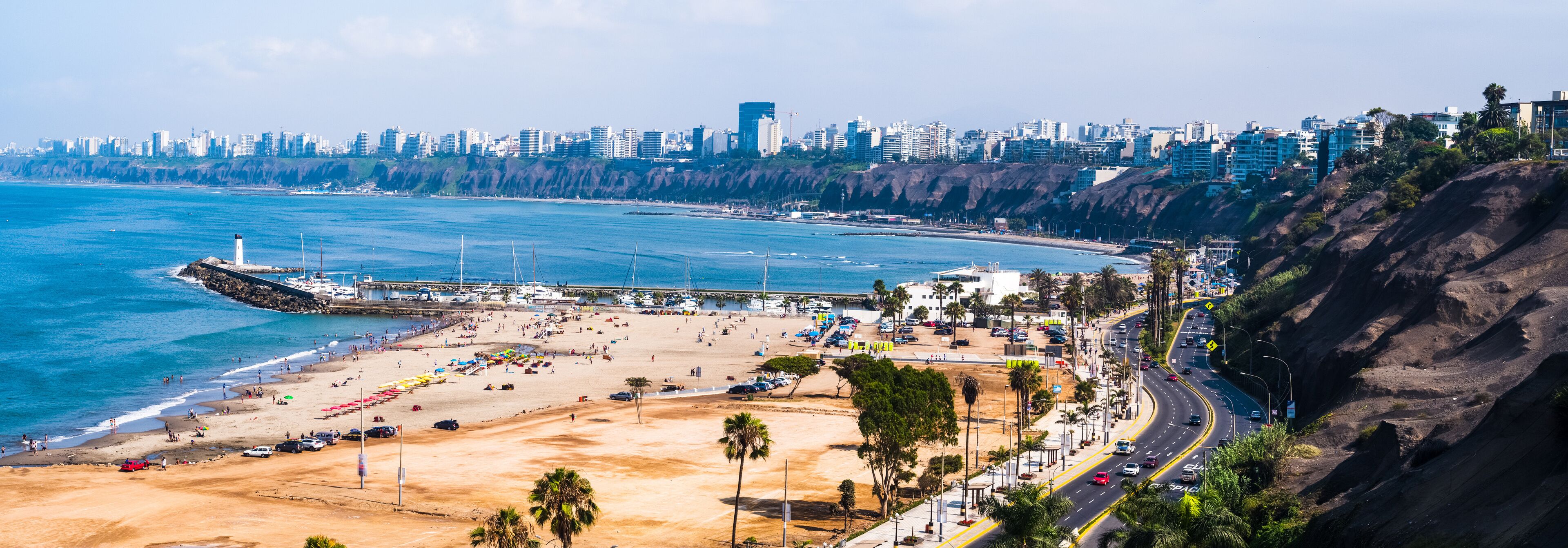 A coastal cityscape with a beach, a lighthouse, and a dense urban skyline.