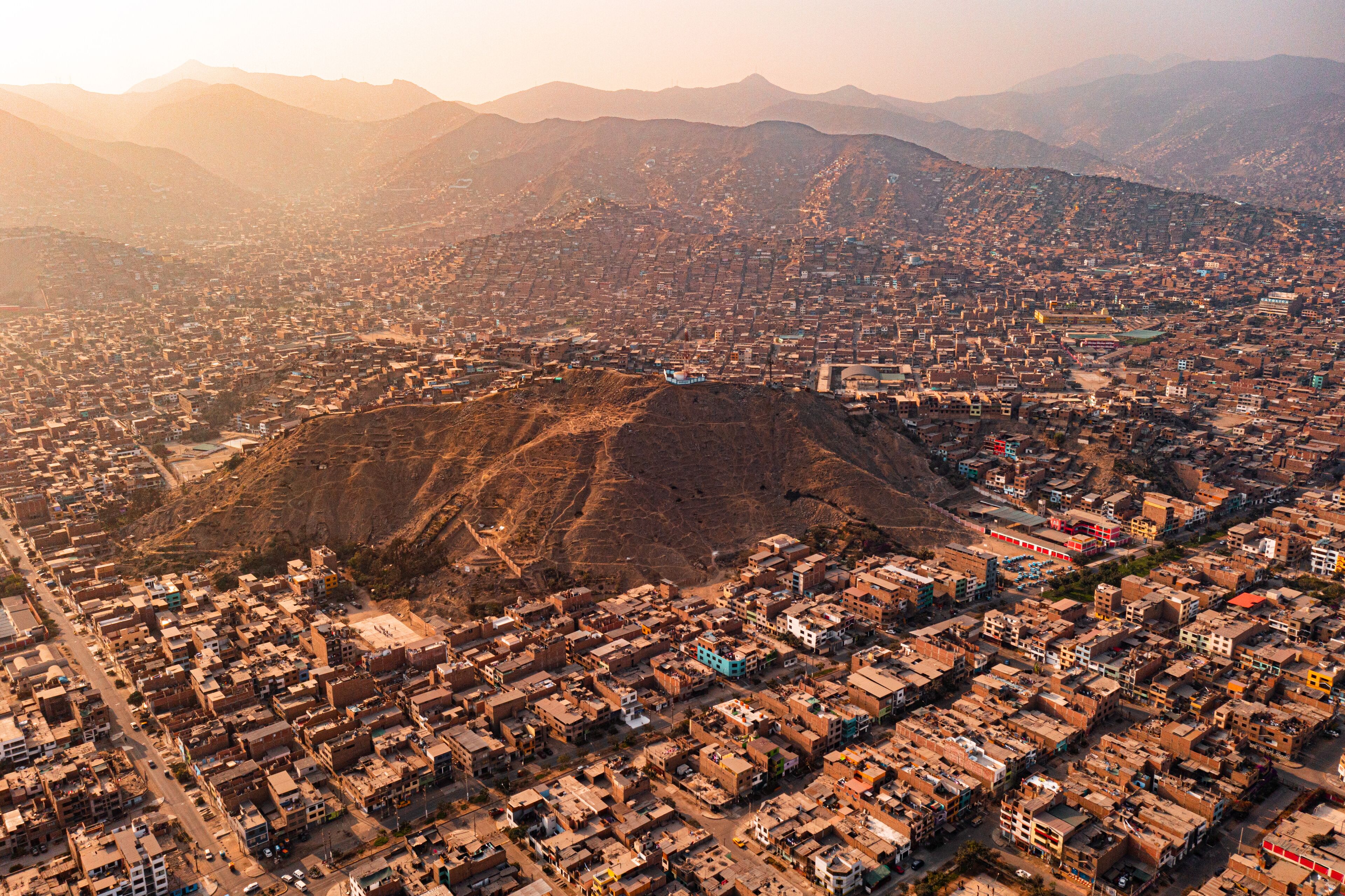 An aerial view of a city with a prominent hill in the center, surrounded by densely packed buildings.
