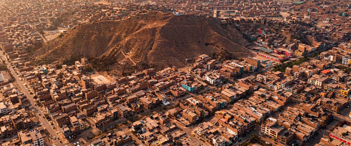 An aerial view of a city with a prominent hill in the center, surrounded by densely packed buildings.