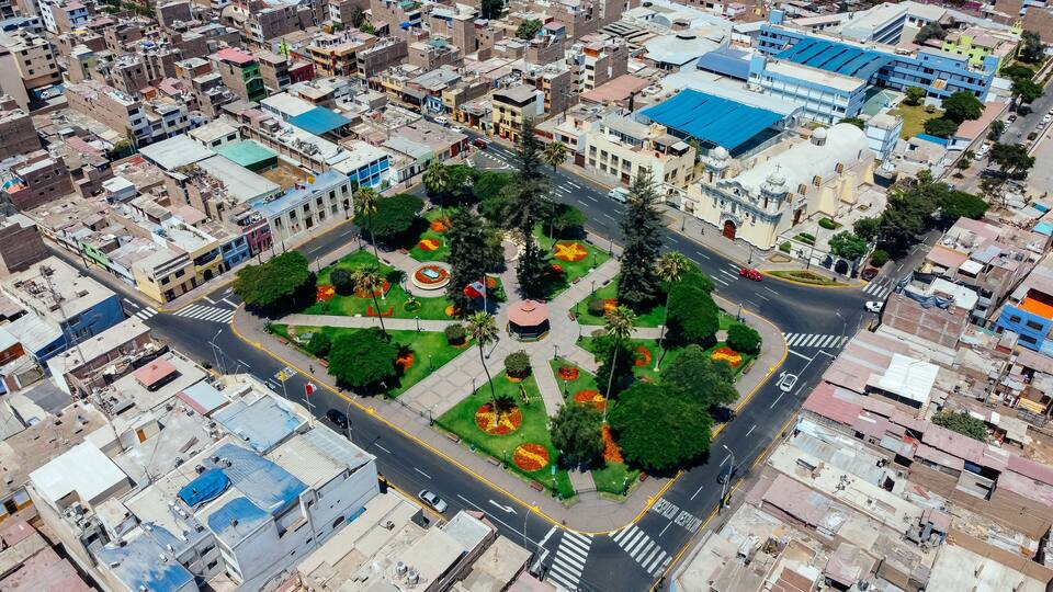 An aerial view of a city with a central park, a roundabout, and surrounding buildings.