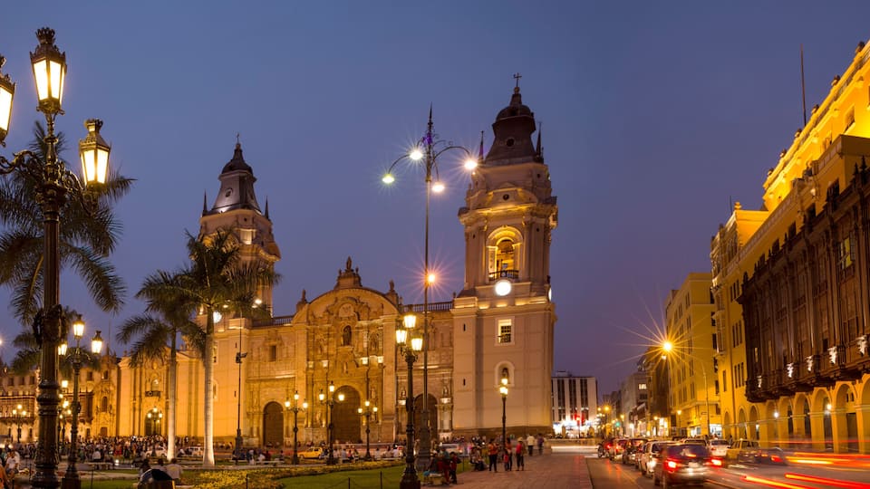 A historic building with a clock tower, surrounded by palm trees and street lamps.